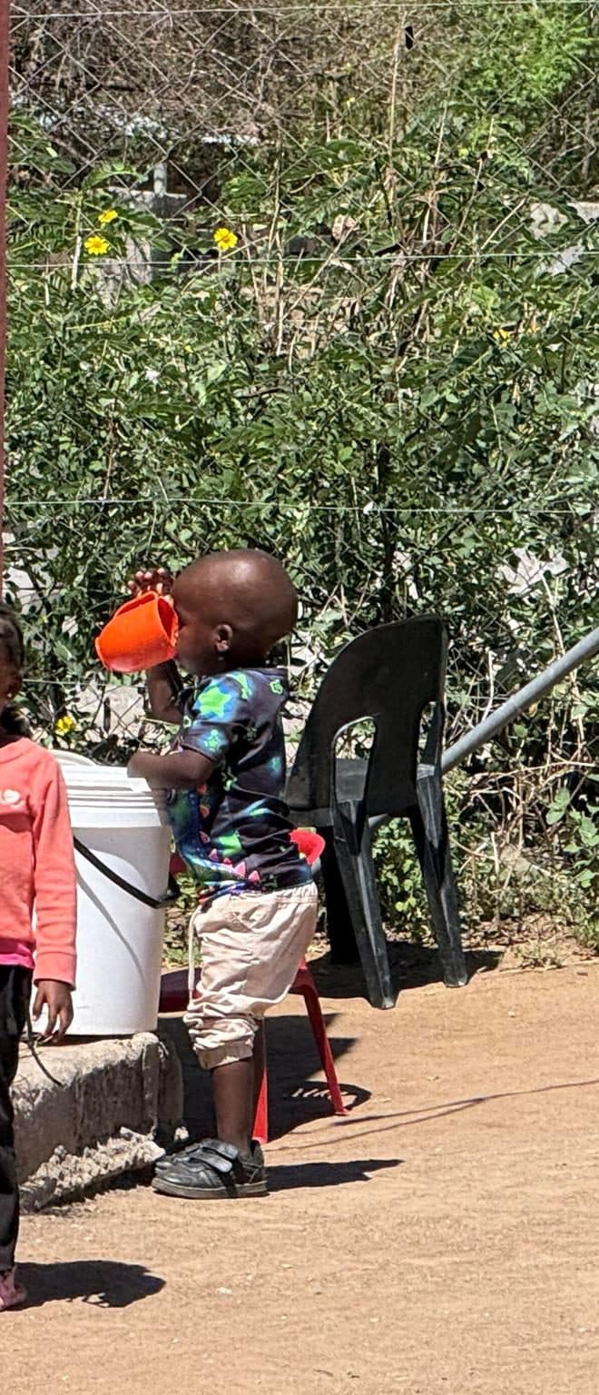 A child drinking water from a communal supply point.