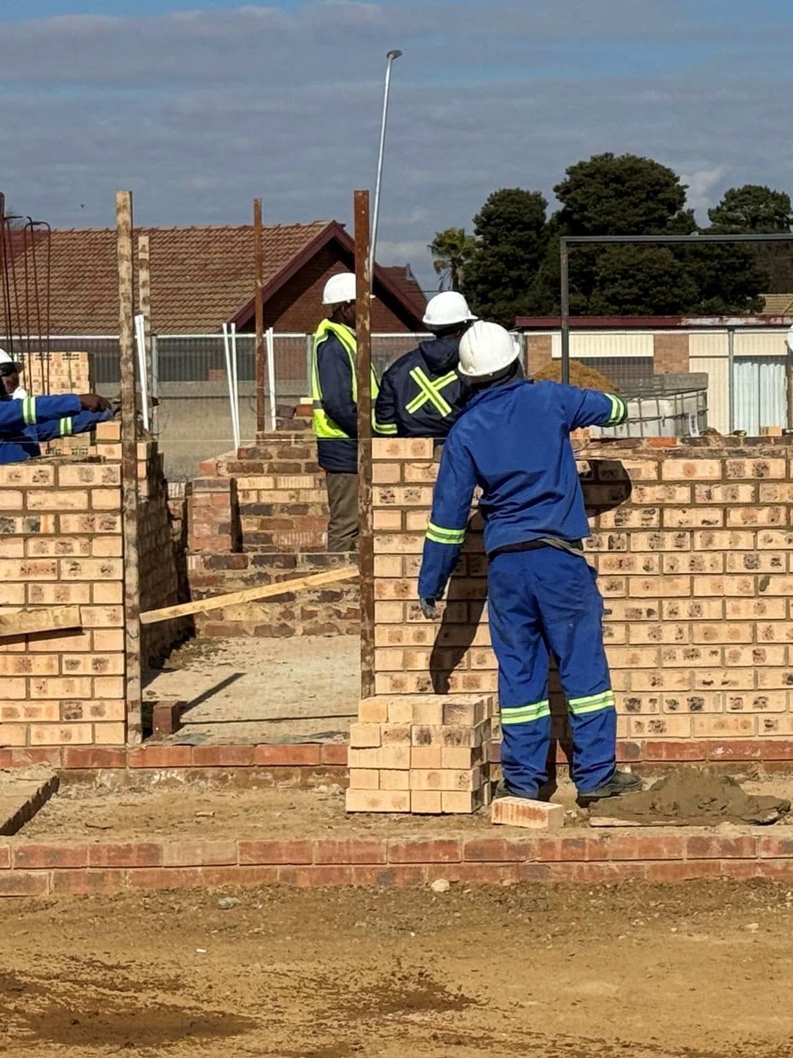 Construction workers laying brickwork on a social infrastructure build.