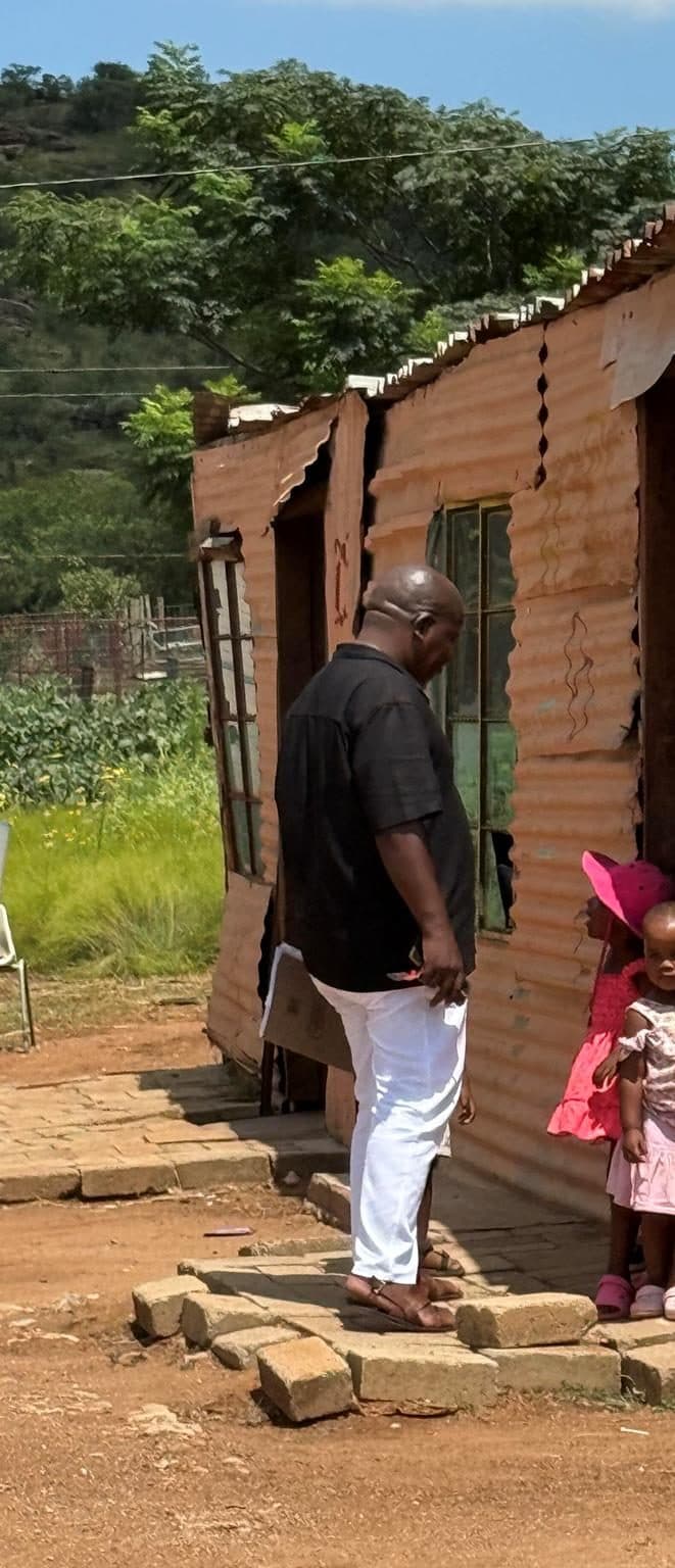 A field researcher speaking with residents outside their home during a needs assessment.