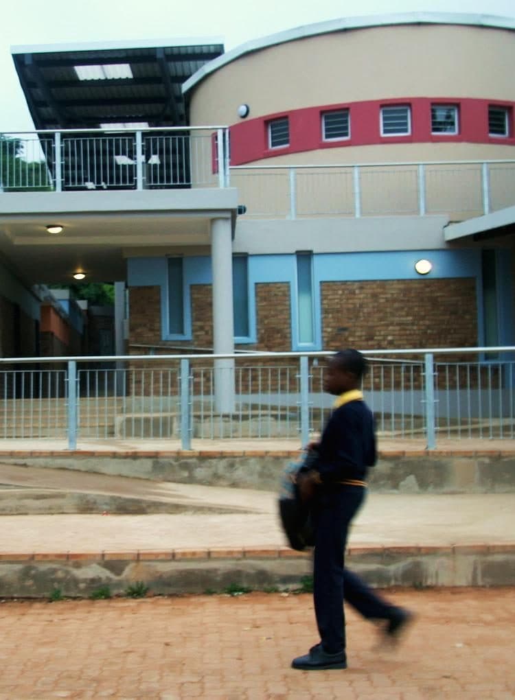 A learner walking past a completed school building.